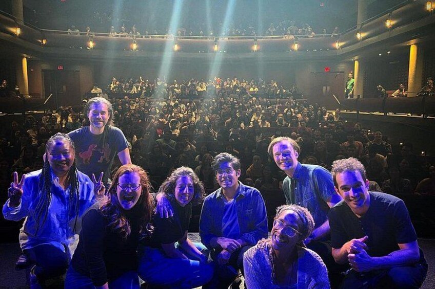 A group of people in a theater with a large audience in the background. 3