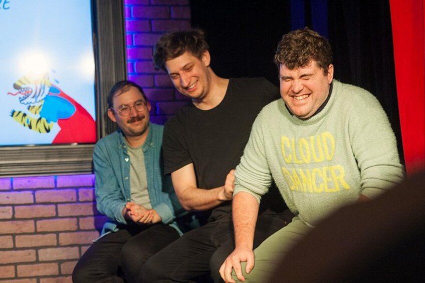 Three people sitting on a stage with a brick wall and a poster in the background. 4