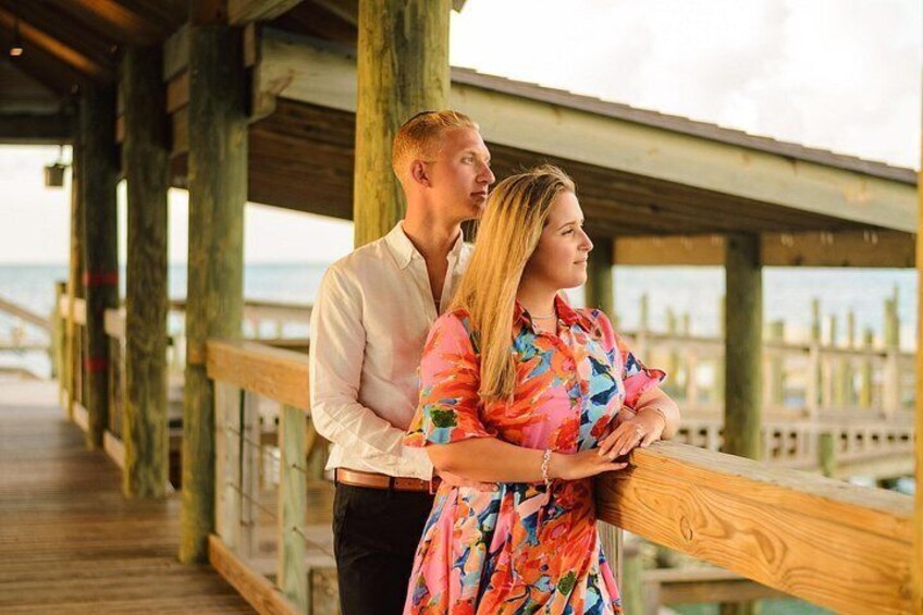 A wooden pier with a railing, a wooden deck, and a view of the ocean. 1