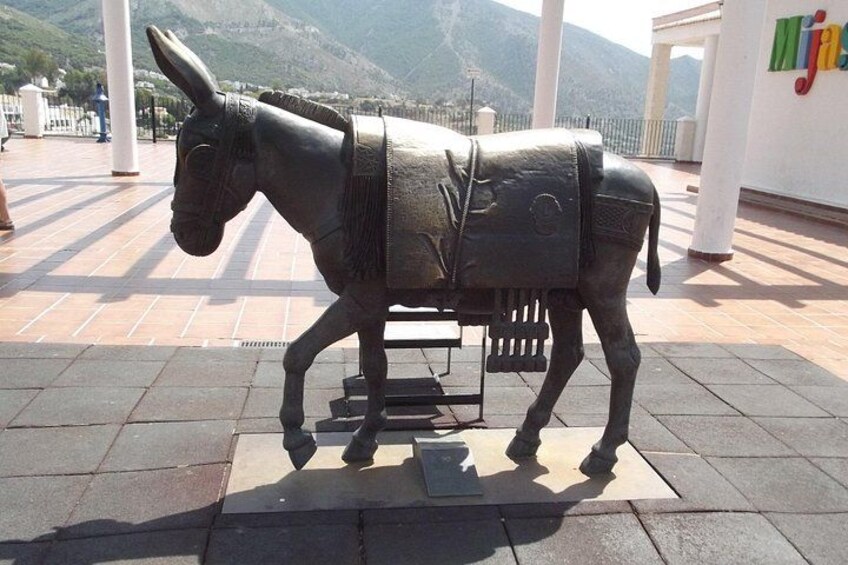 A donkey statue on a tiled plaza with mountains in the background. 4