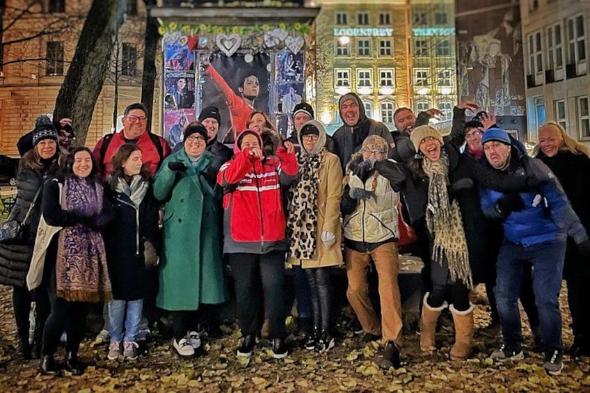 A group of people posing for a photo in an urban setting with buildings in the background. 2