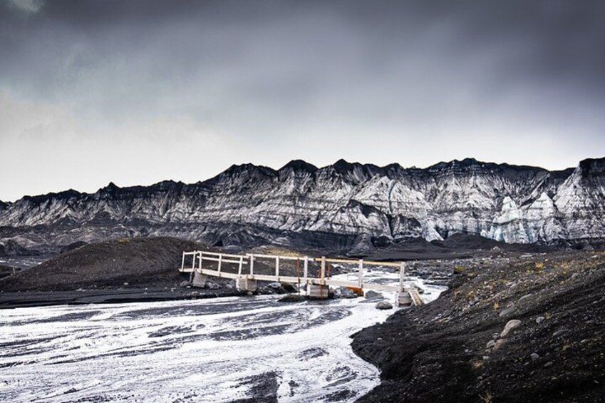 Un paisaje nevado con una estructura de madera y una cadena montañosa rocosa. 5