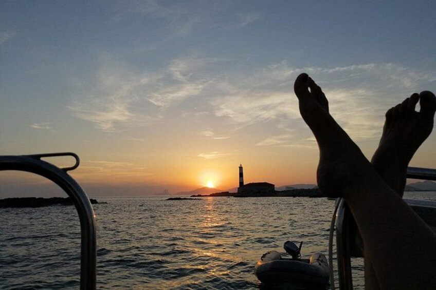 Un atardecer sobre el agua, con un faro a lo lejos. 2