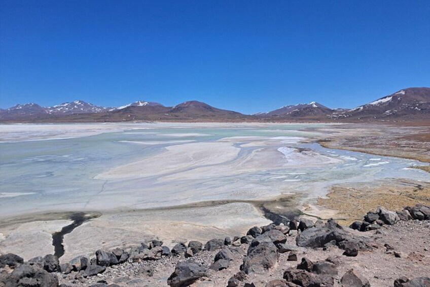 Una distesa salata con depositi minerali e montagne sullo sfondo. 2