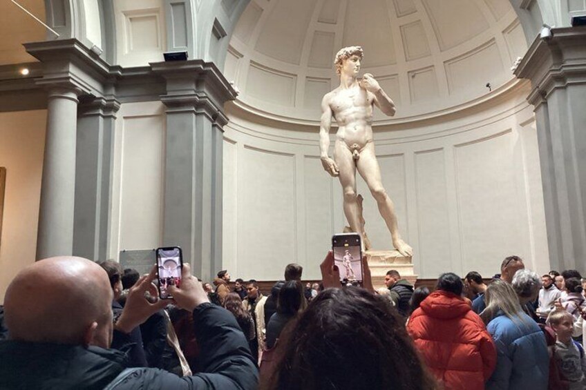 A classical statue in a grand hall with a crowd taking photos. 2