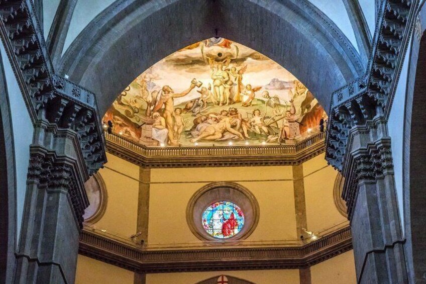 A cathedral interior with a large stained glass window and a detailed fresco on the ceiling. 5