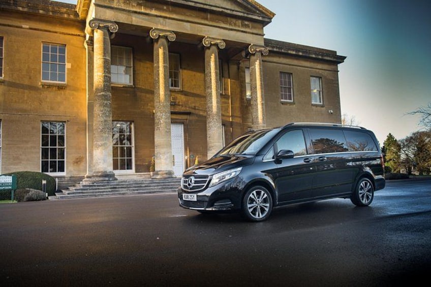 A black van parked in front of a classical building with columns. 3