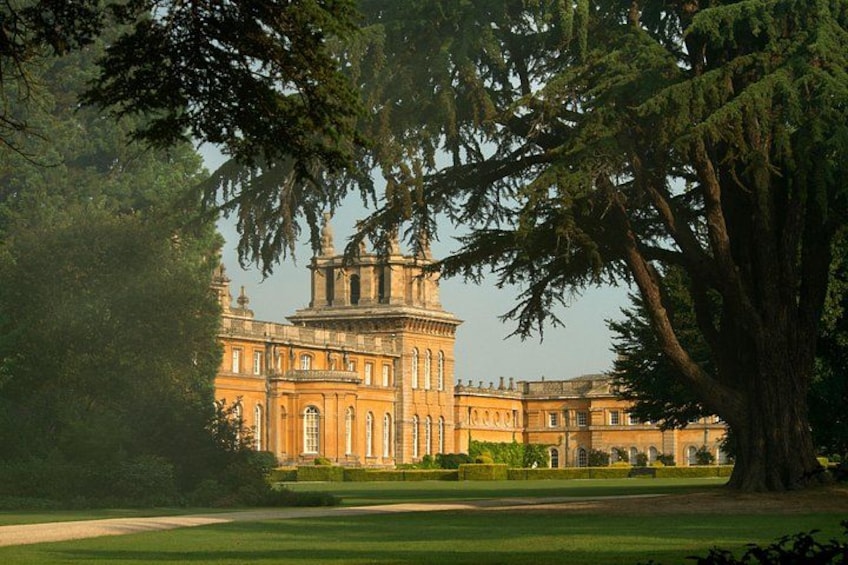 A large, historic building with a prominent tower, surrounded by lush greenery and a well-maintained lawn. 4