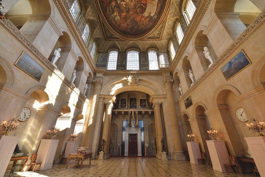 An ornate hall with high ceilings, arched windows, and classical statues. 2