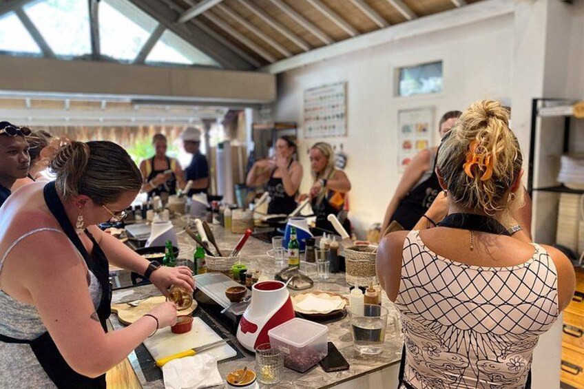 A group of people engaged in a cooking activity, with cooking utensils and ingredients on the table. 3