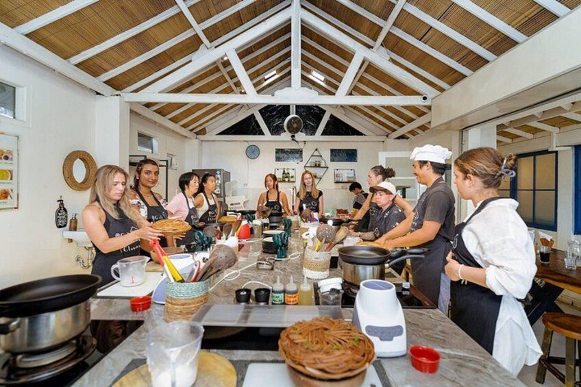A group of people cooking in a kitchen with a high ceiling and wooden beams. 2