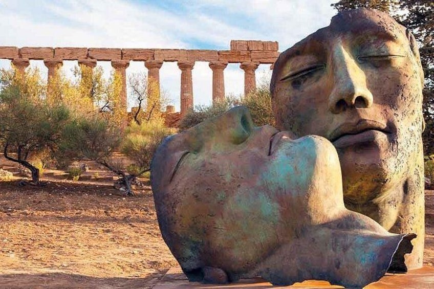 A large stone sculpture in an outdoor setting with a historical building in the background. 5