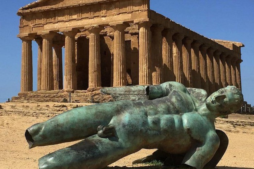 A large ancient Greek temple with columns and a bronze statue of a reclining man. 1