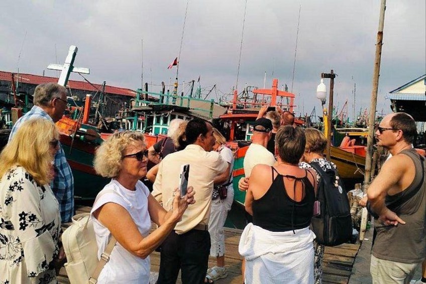 A group of people standing on a dock with boats in the background. 4