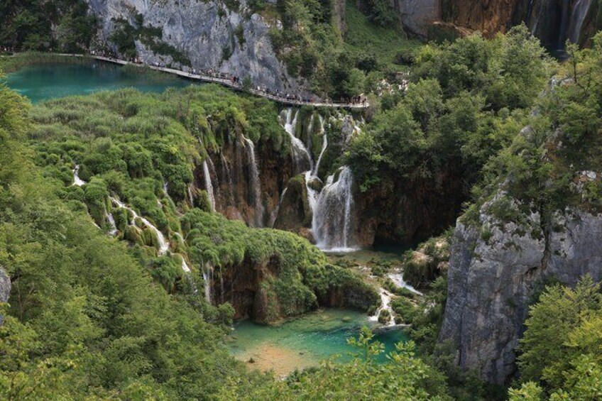 A multi-tiered waterfall surrounded by lush greenery and a viewing platform. 2