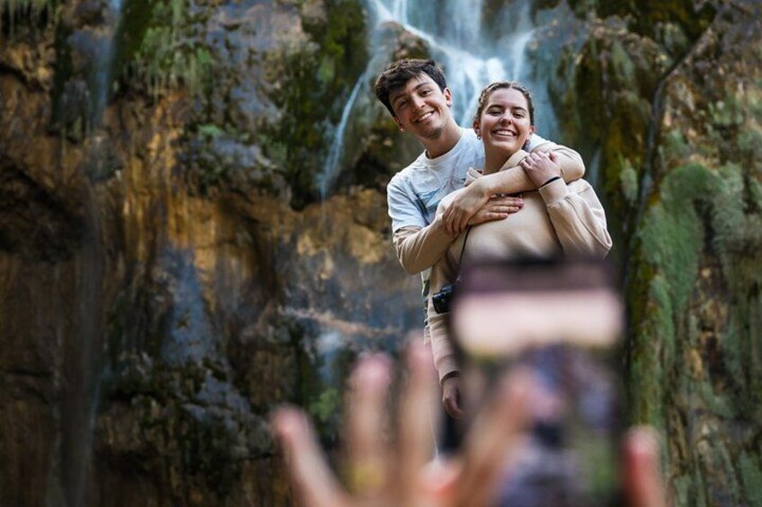 A couple embracing in front of a waterfall with rocky terrain. 2