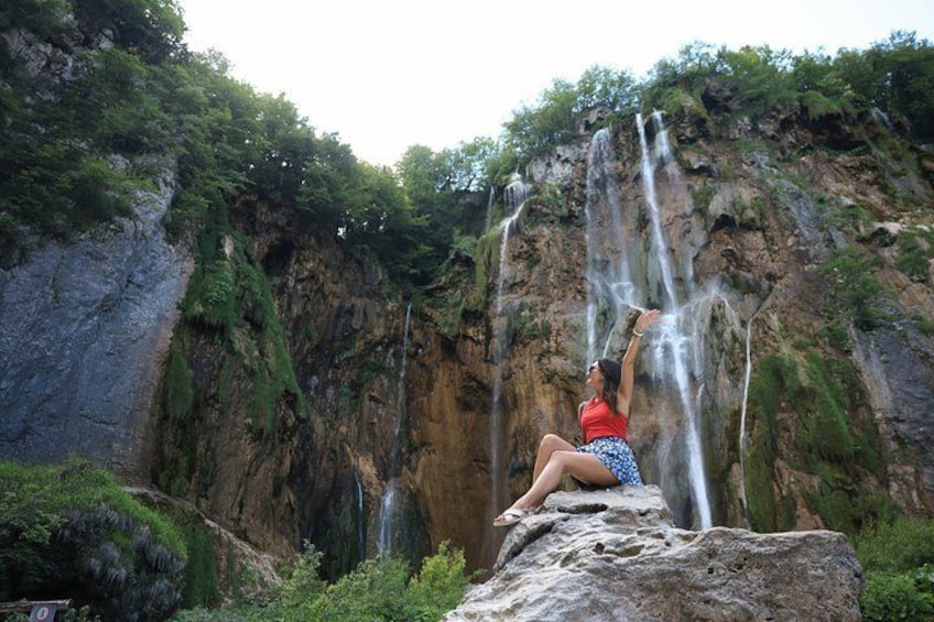 A person sitting on a rock by a waterfall. 3