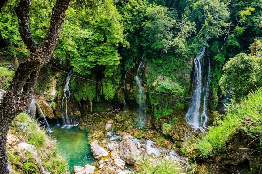 Una cascada que se precipita sobre rocas hacia una piscina cristalina, rodeada de vegetación exuberante. 5