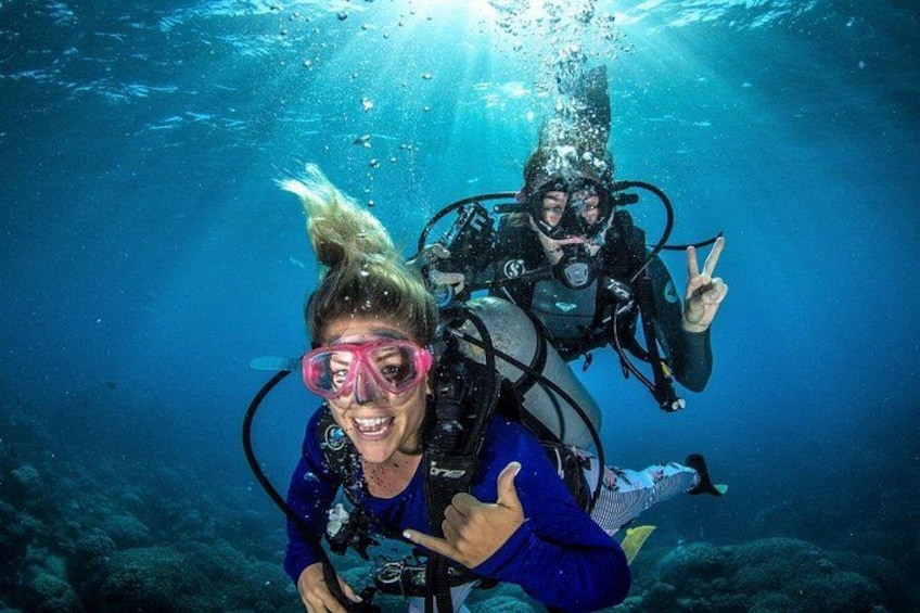 Two scuba divers underwater with bubbles and a diver making a peace sign. 1