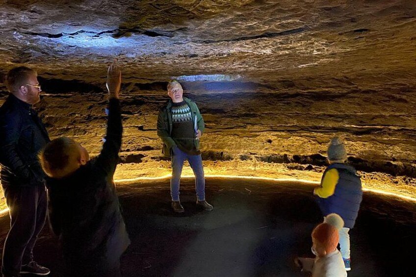 A group of people inside a cave with a person standing on a platform. 2