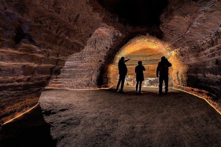 A cave with three people observing the interior. 4