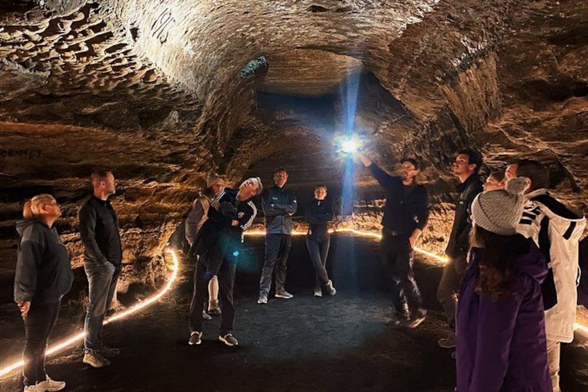 A group of people inside a cave with a light source at the end of a tunnel. 3