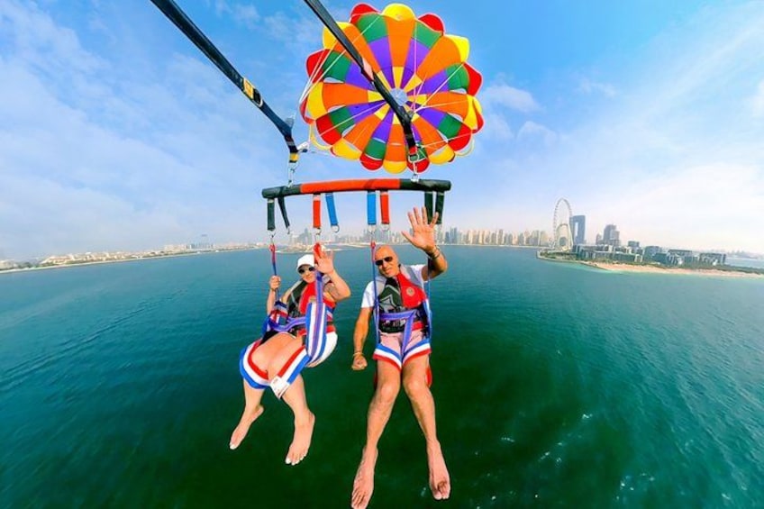 Two people skydiving with parachutes over a body of water, with a city skyline in the background. 4