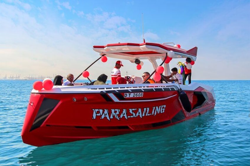 A red parasailing boat with passengers on the water. 2