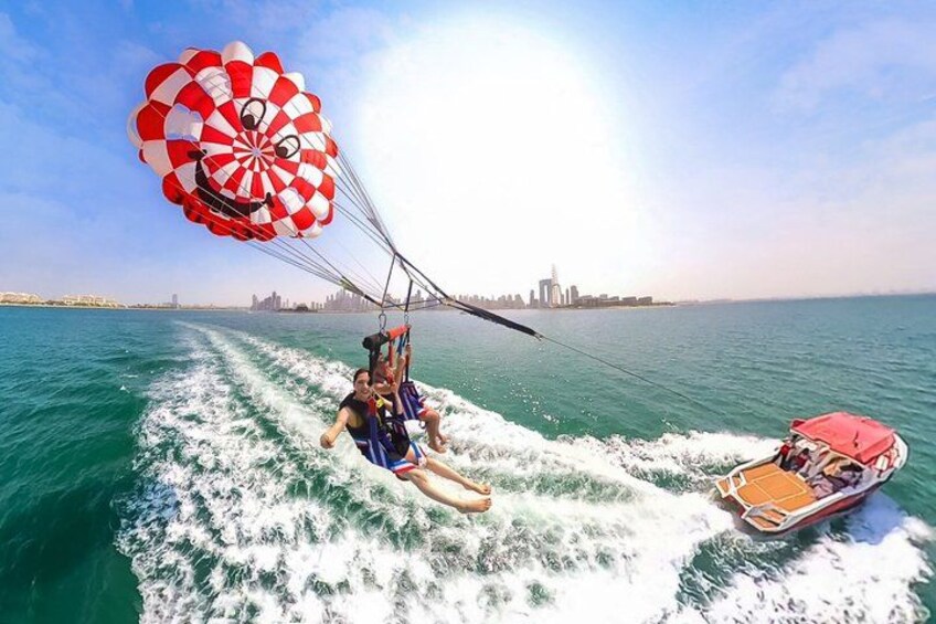 A parasailing activity over water with a city skyline in the background. 3