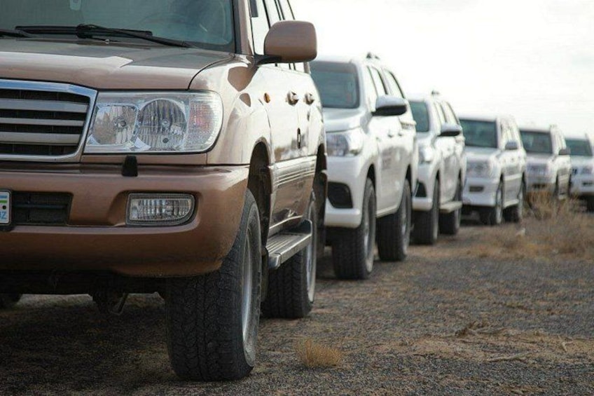 A row of off-road vehicles parked on a gravel surface. 3