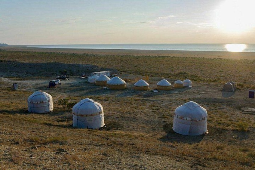Yurts in a desert landscape with a body of water in the background. 5