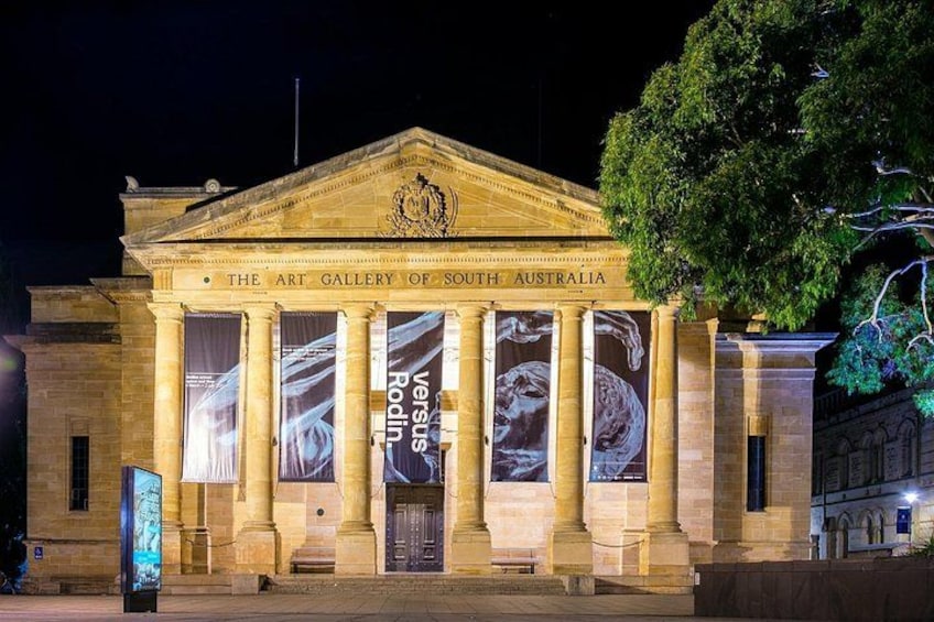 La Galería de Arte de Australia Meridional de noche, con columnas iluminadas y grandes pancartas. 5
