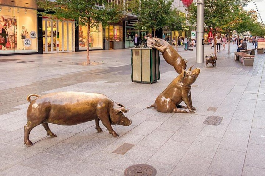 Una plaza pública con una estatua de un cerdo y un cerdo acostado. 3