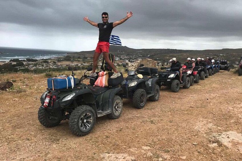 A person standing on an ATV with a group of ATVs parked in a line on a dirt path. 3