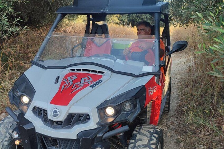 A red and white ATV on a dirt path with vegetation on the sides. 4