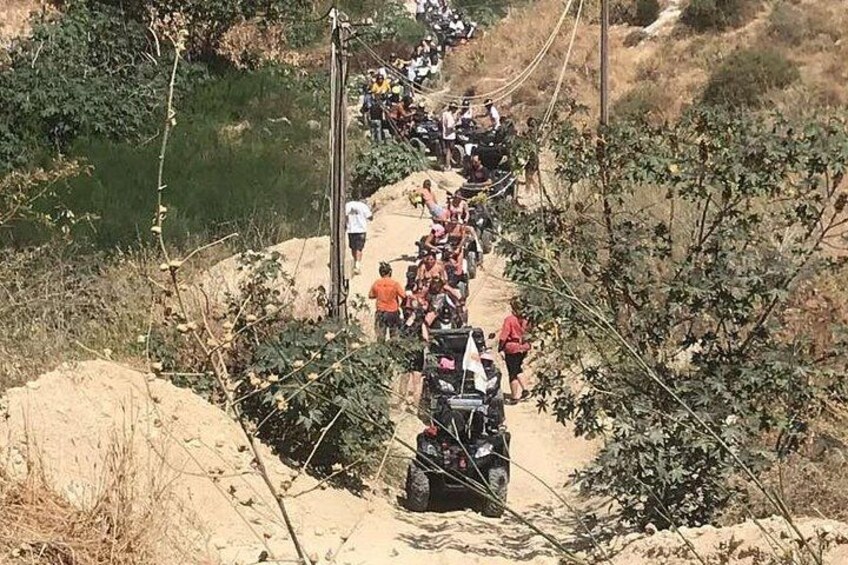 A group of people on ATVs on a dirt path surrounded by vegetation. 2
