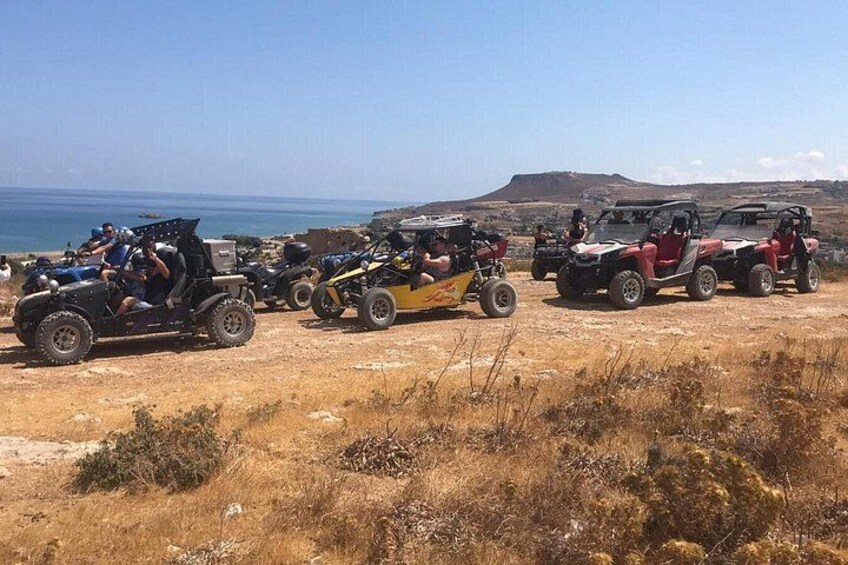 Off-road vehicles on a dirt path with a coastal landscape in the background. 5