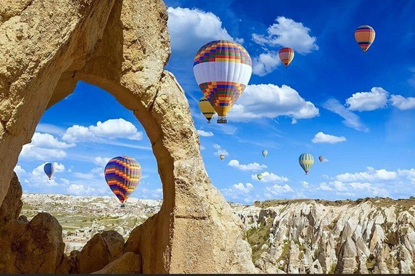 A landscape with a rock arch and hot air balloons in the sky. 5