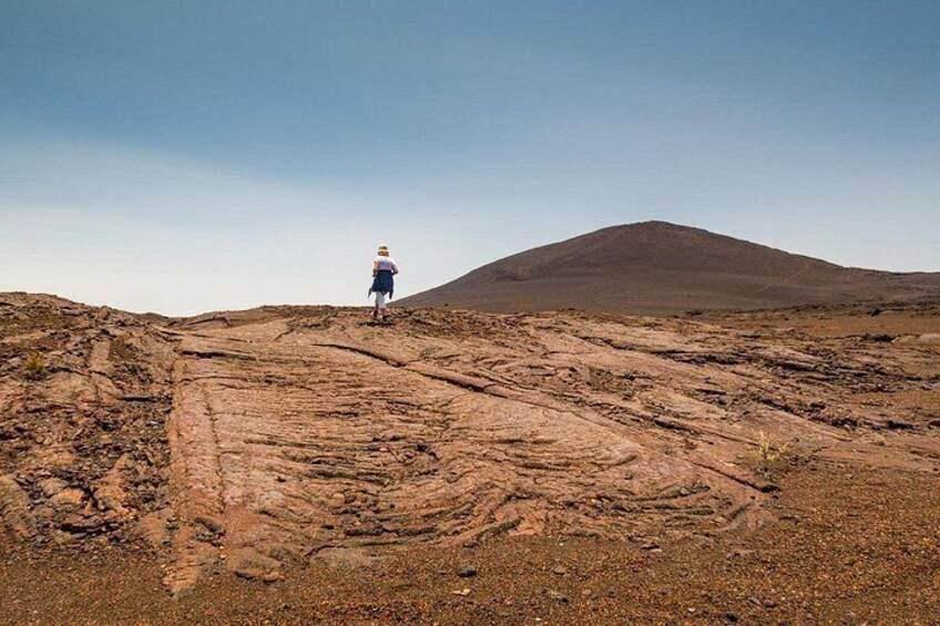 Una persona caminando sobre terreno rocoso, con una colina al fondo. 2