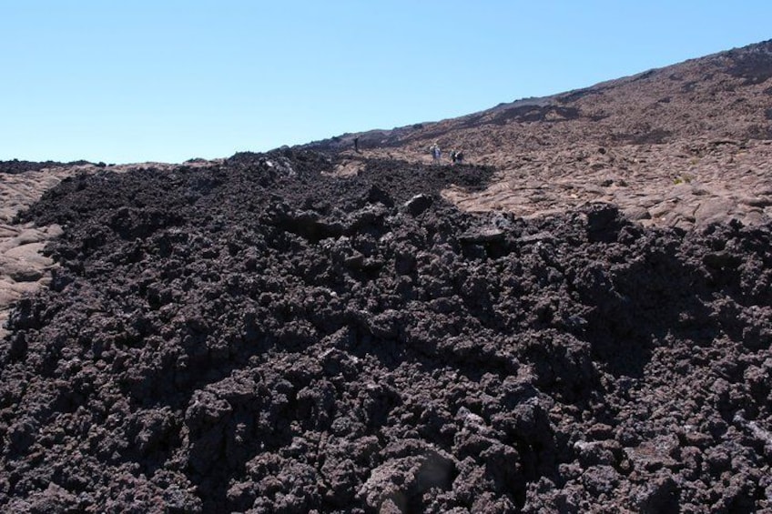A volcanic landscape with rugged terrain and sparse vegetation. 2