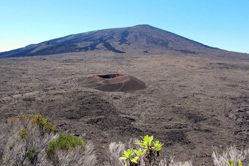 A barren landscape with a prominent hill and a crater. 1