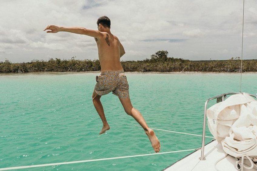 A person jumping off a boat into turquoise water. 3