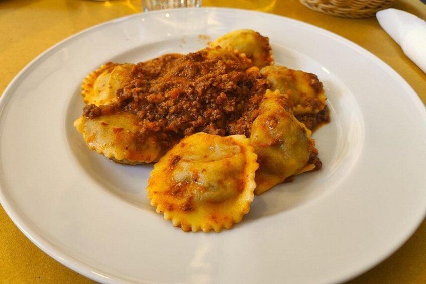 A plate of ravioli with a meat sauce. 4