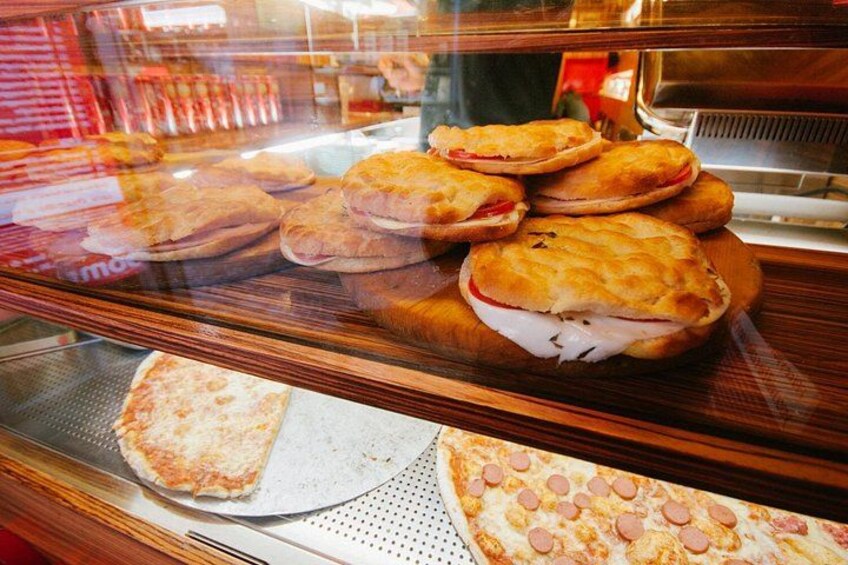 A bakery display case with various baked goods, including pastries and pizzas. 3