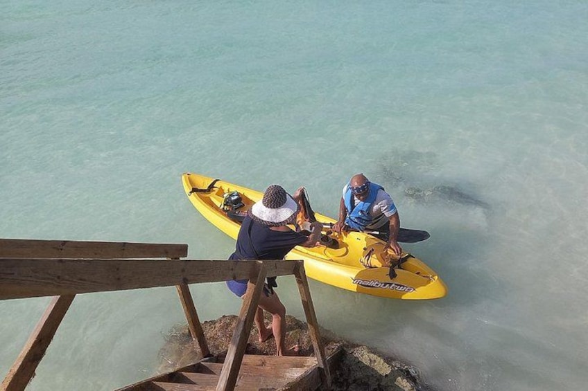 Two people in a yellow kayak on a calm body of water, with a wooden dock in the foreground. 5