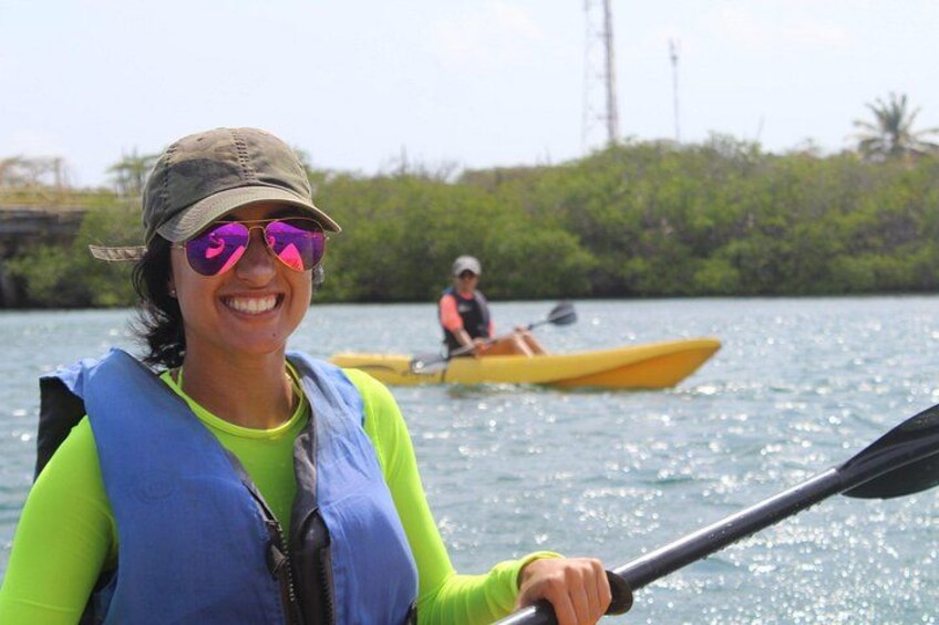A person in a kayak on a body of water with greenery in the background. 2