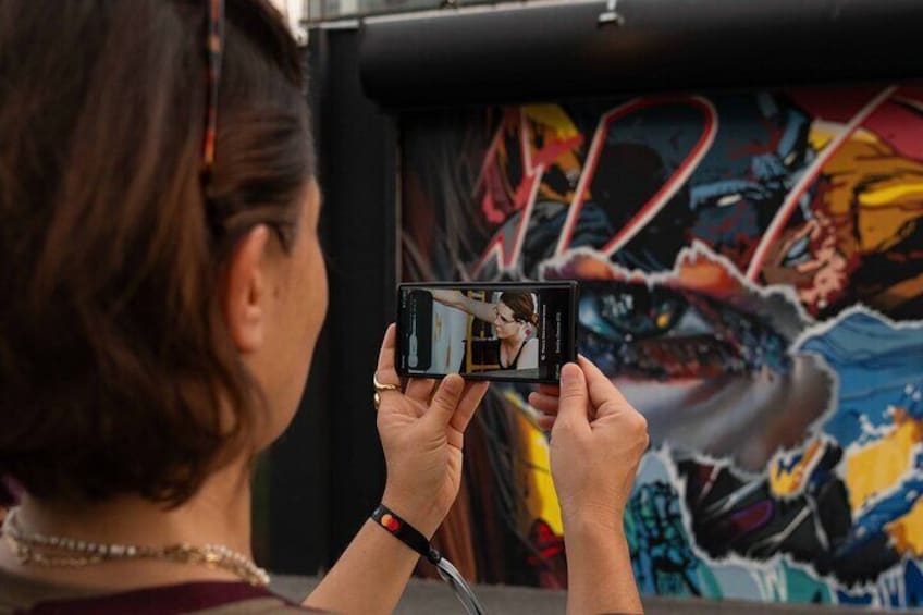 A person taking a photo of a colorful mural. 5