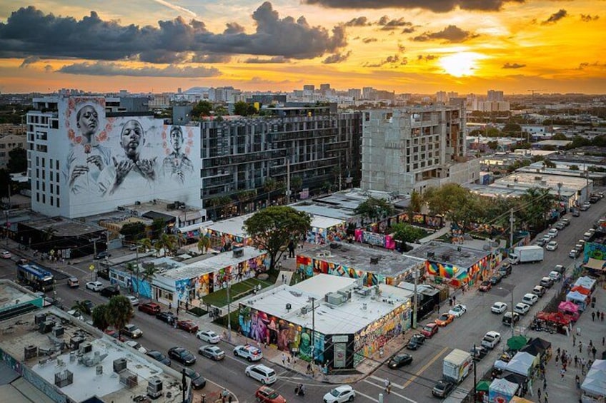 Paesaggio urbano con un murale su un edificio, una strada trafficata e un tramonto. 4