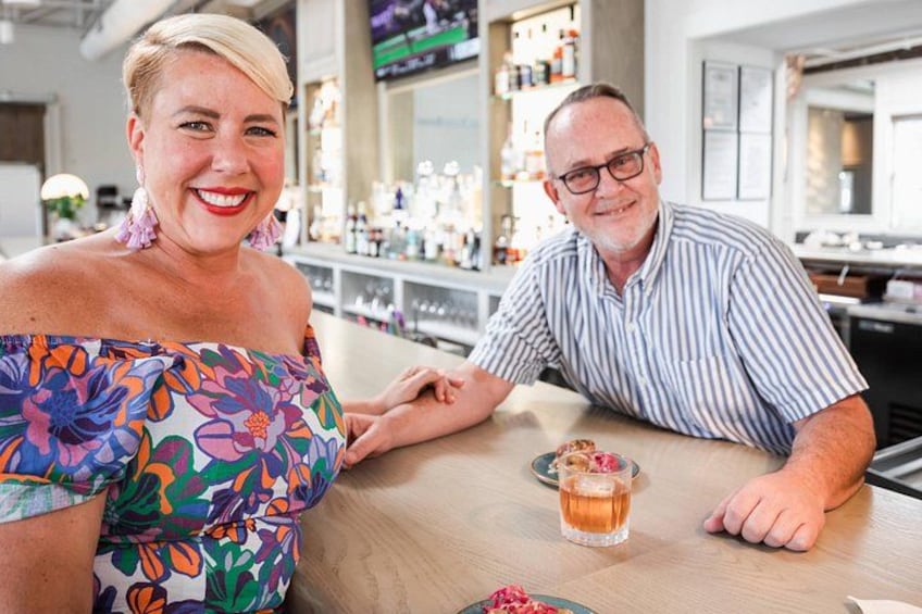 Two people sitting at a bar with a drink in front of them. 2