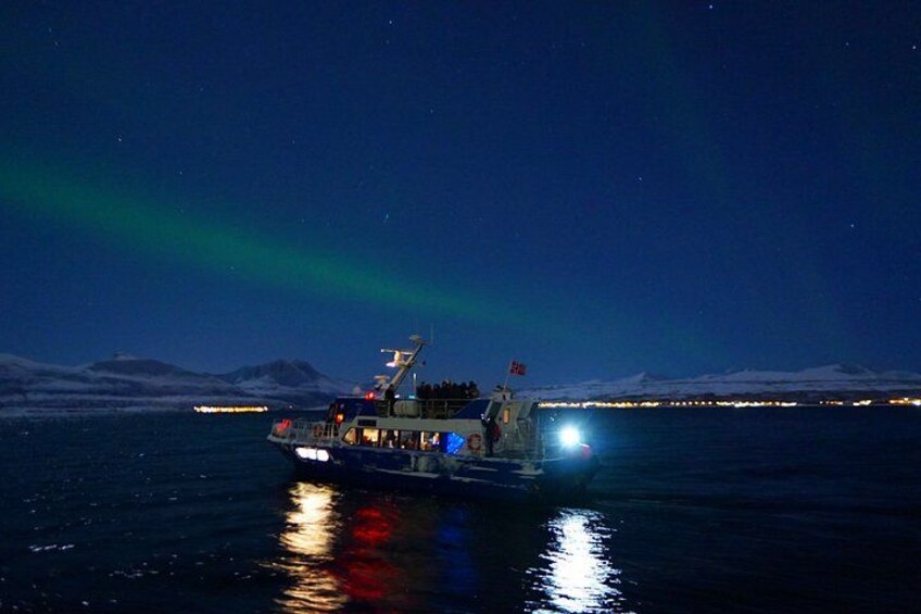 A boat on a dark sea with the Northern Lights in the background. 2
